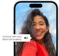 iPhone 15 يعرض ميزة التعليق الصوتي التي تعلن عن معلومات الصورة، شخص ذو شعر أسود مموج يضحك