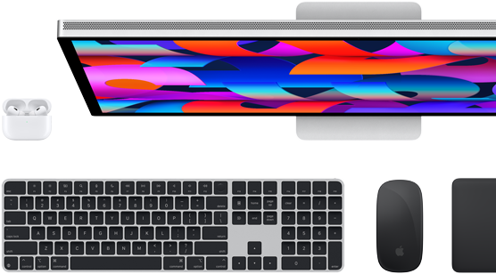 منظر من أعلى لأسفل لشاشة Studio Display ولوحة المفاتيح Magic Keyboard السوداء وماوس Magic Mouse الأسود ولوحة التتبع Magic Trackpad السوداء وحافظة AirPods البيضاء