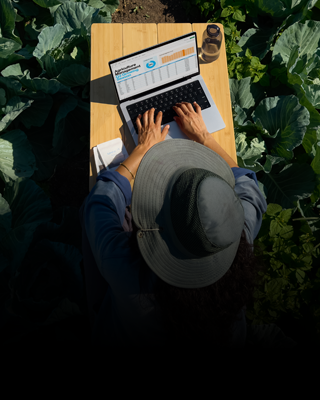 A person works on a 14-inch MacBook Pro in Silver without a charge cable, while sitting at an outdoor table in the sun